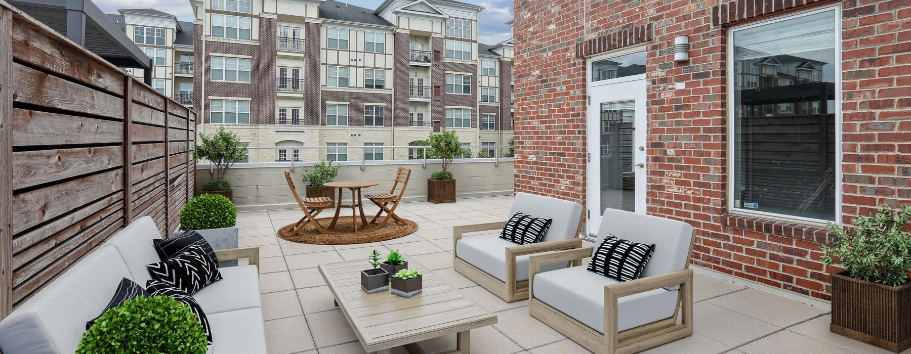 a patio with a table and chairs and a patio with plants and a building in the background