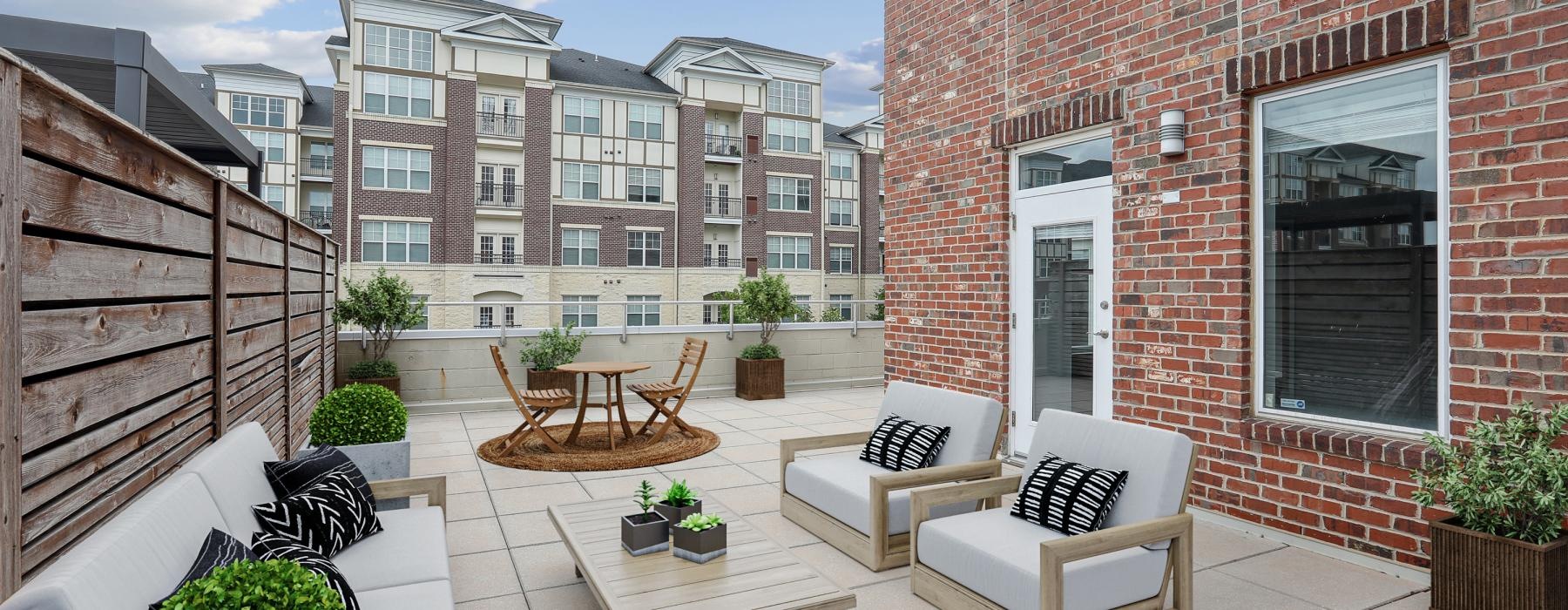 a patio with a table and chairs and a patio with plants and a building in the background